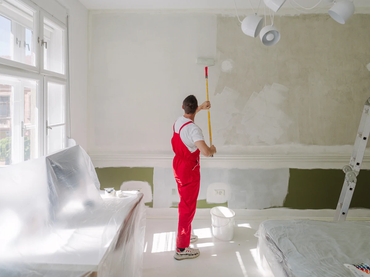 Professional painter in red overalls doing radiator finishes